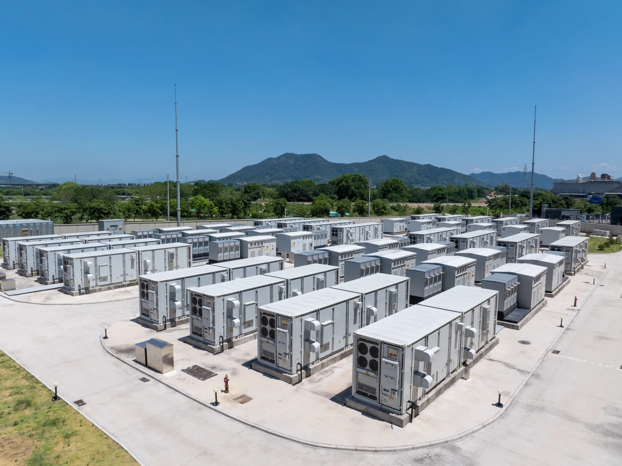 Rows of utility-scale battery energy storage containers under a mountain sky