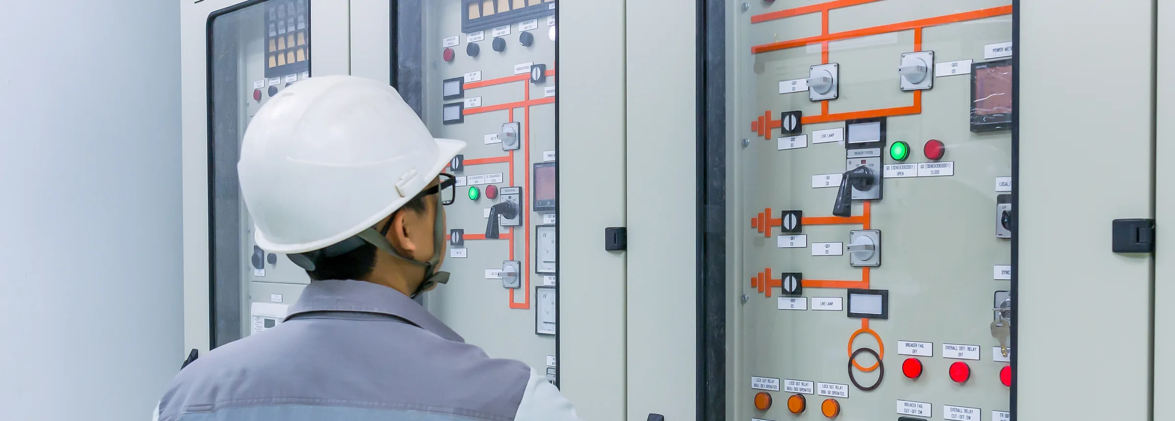 Technician at a control and protection panel in a substation control house