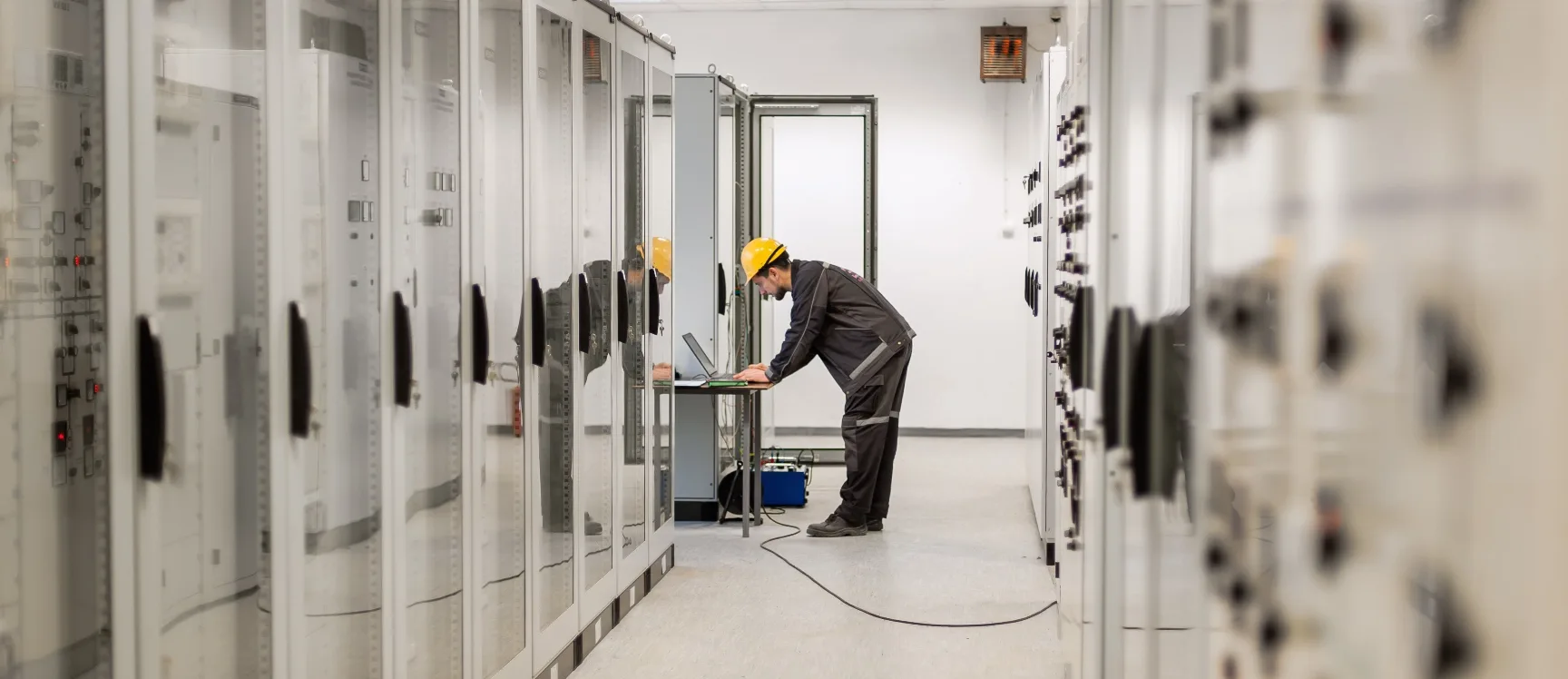 Technician inspecting switchgear in an electrical room