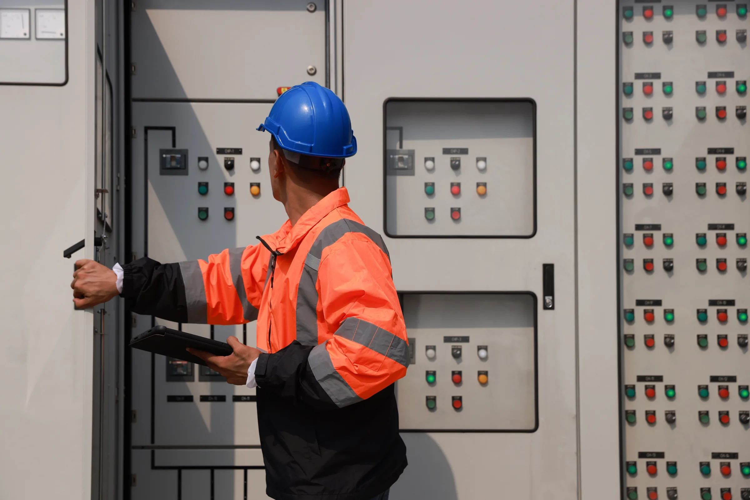 Technician in a hard hat working at a protection panel